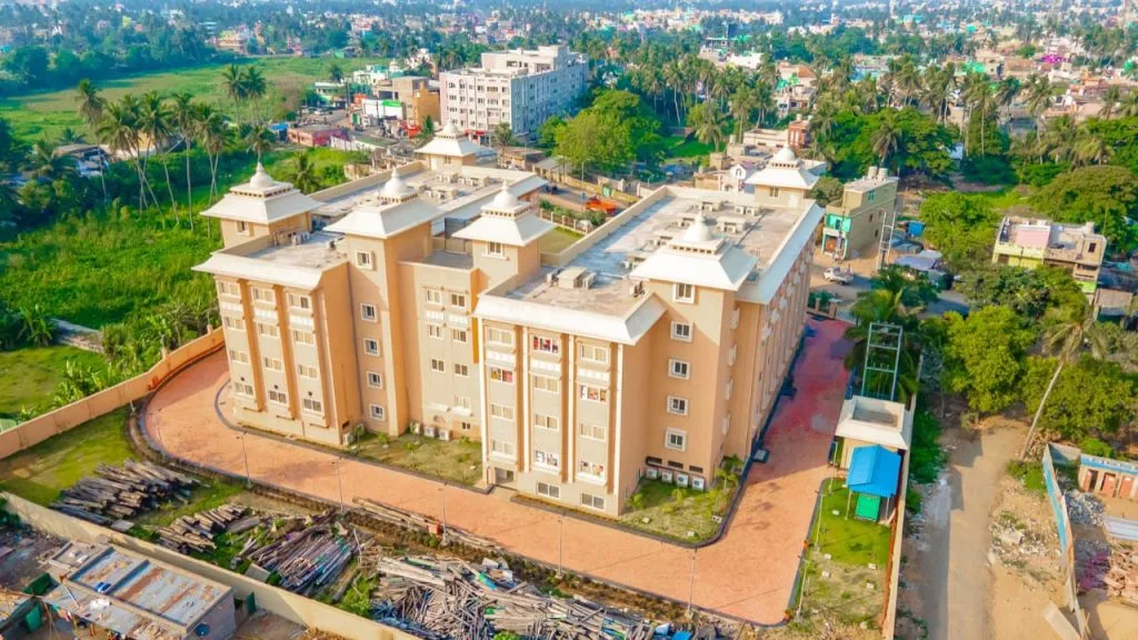 A clean and peaceful accommodation building with a simple, traditional design, showcasing a welcoming entrance, neatly maintained surroundings, and a calm environment suitable for pilgrims and travelers staying at Purushottam Bhakta Nivas.